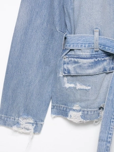 Détail d'une veste en jean bleu clair délavé avec déchirures et ceinture assortie
