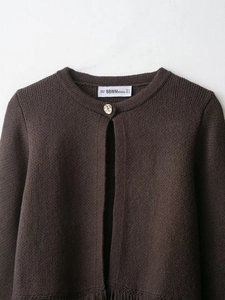 Close-up of knit cardigan showing textured fabric and embossed gold button detail