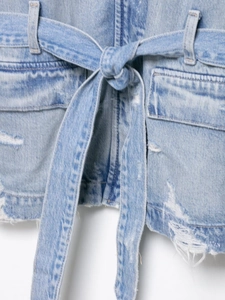 Détail de la taille d'une veste en jean bleu clair avec ceinture et texture vieillie