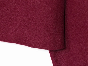 Detailed macro shot of burgundy wool fabric texture on a long sleeve outerwear