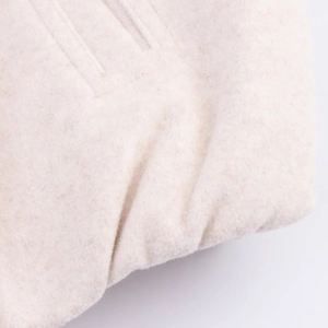 Detail showing soft oatmeal wool texture and precise pocket stitching of the bomber jacket