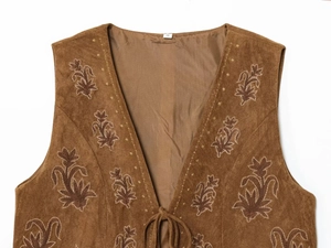 Détail du gilet en daim marron avec broderies florales rouges et fermeture à cordon de serrage