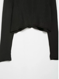 Détail du cardigan en maille côtelée noire avec ourlet ondulé et texture fine