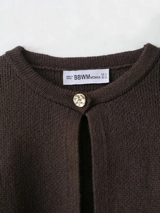 Detail of round neck brown knit cardigan with gold button and woven brand label