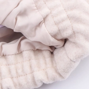 Detailed macro view of quilted beige aviator jacket showing soft fleece and satin lining