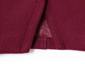 Detail of burgundy wool coat hem with precise stitching and matching satin lining