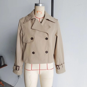 Close-up of khaki double-breasted short trench coat with wide lapels and epaulettes