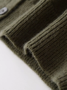 Macro shot of olive green wool blend knit cardigan with ribbed cuffs and grey button detail