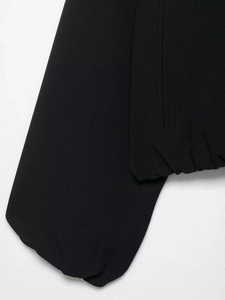 Détail de la veste noire avec ourlet élastique et coutures de poche sur le tissu lisse