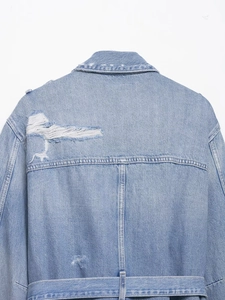 Détail du dos d'une veste en jean bleue avec texture déchirée et ceinture assortie