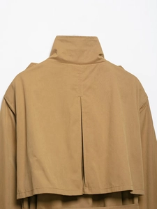Detail view of khaki trench coat back with layered storm flap and center pleat design