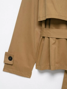 Close-up of khaki trench coat featuring cuff straps, round buttons, and cotton twill texture