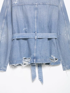 Détail de la veste en jean bleu clair avec ceinture et déchirures style vintage rétro