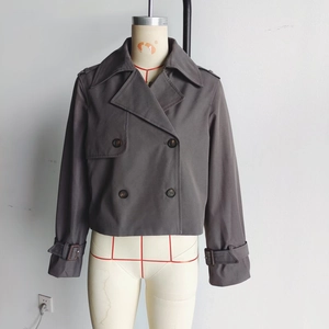 Detail view of charcoal grey cropped trench jacket with double-breasted buttons and lapels
