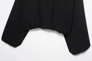 Gros plan sur l'ourlet de veste noir et poignets élastiques avec détails de couture
