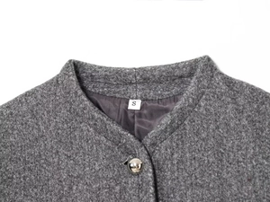 Macro view of grey woolen jacket collar with silver spherical button and size S tag