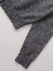 Detail of dark grey wool blend cardigan featuring ribbed cuffs and fine knit texture