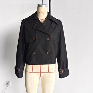 Detail of short double-breasted black trench jacket with adjustable cuff straps and lapel