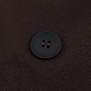 Macro shot of a dark brown four-hole button on the fabric of the women oversized blazer