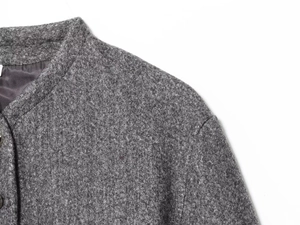 Detailed view of grey wool coat featuring high collar and textured tweed fabric material