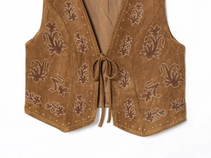 Détail d'un gilet en daim marron avec broderies florales et fermeture à lacets frontale