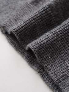 Detailed macro shot of dark grey ribbed knit texture on a premium wool cardigan sweater