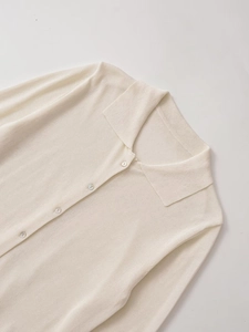 Detail view of cream white knit cardigan showing fine texture and pearlescent buttons