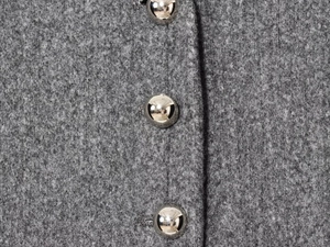 Detail of silver spherical metal buttons on grey textured wool jacket fabric