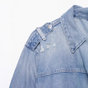 Veste en jean bleu clair avec délavage vintage, épaulettes et boutons métalliques