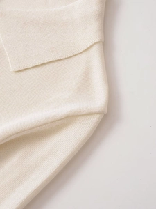 Detailed close-up of soft off-white knit texture and fine stitching on a polo cardigan