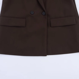 Detail of dark brown double-breasted blazer showing flap pockets and buttons