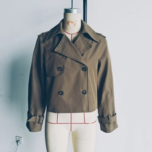 Detail of dark olive short double-breasted trench coat with shoulder epaulettes and buckles