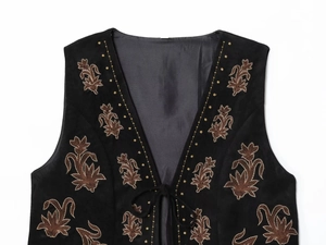 Gros plan détaillé des broderies florales sur gilet noir en suédine avec col en V