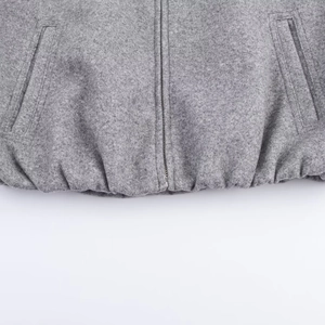 Detail of grey wool bomber jacket showing the metal zipper and elastic hemline