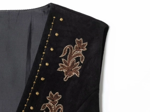 Gros plan d'une broderie rétro sur gilet en daim noir avec motifs de feuilles