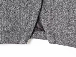 Close-up of grey wool fabric texture showing detailed hem slit and smooth black silk lining