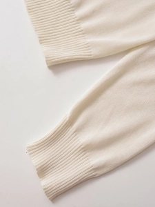 Detailed view of ribbed cuffs and fine knit texture on a cream polo cardigan