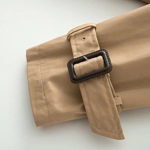 Detailed view of khaki trench coat cuff featuring adjustable strap and faux leather buckle