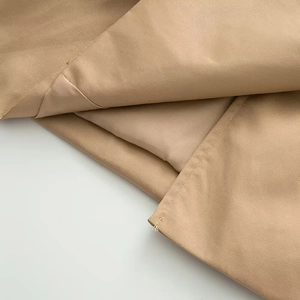 Detail shot of the khaki trench coat showing the twill fabric texture and smooth lining