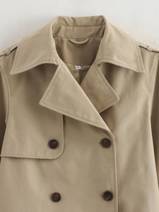 Detail view of khaki double-breasted trench coat with classic lapels and tortoise buttons