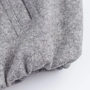 Close-up of the thick grey wool blend fabric texture on women's bomber jacket sleeve