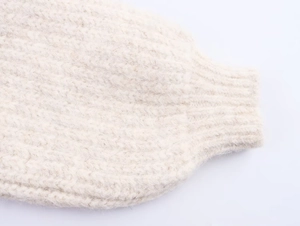 Detailed close-up of chunky knit sweater cuff showing soft off-white wool texture