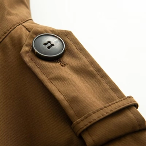 Close-up of camel brown trench coat featuring epaulet detail and dark button finish