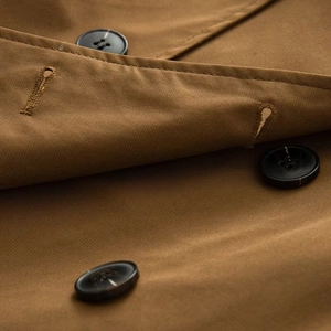 Macro shot of camel twill fabric texture and marble resin buttons on short trench coat