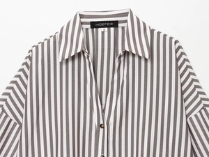 Close-up of linen striped shirt neckline featuring brand tag and amber-style buttons