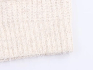 Close-up of cream knit sweater showing dense texture and ribbed hem detail