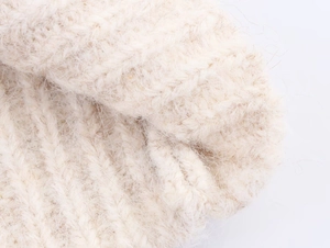Detail of soft cream white cable knit texture showing plush yarn and warm ribbed fabric