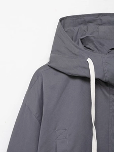 Detailed macro view of gray hooded jacket with white drawstrings and reinforced stitching