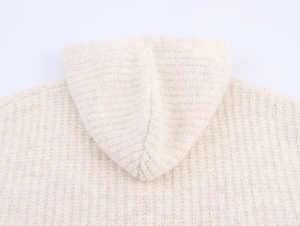 Close-up detail of cream chunky knit texture and hood seam on oversized cardigan