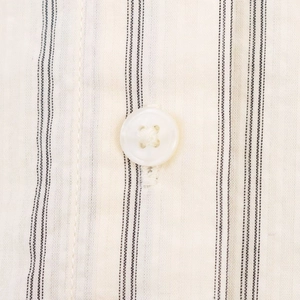 Détail macro d'une chemise à rayures montrant le bouton blanc et la texture de couture